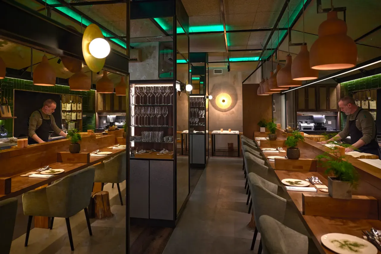Comedor de El Invernadero visto a lo largo, con las lámparas de cobre encendidas sobre las mesas